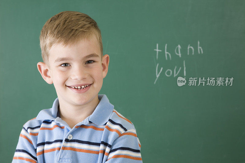 可爱的小男孩在学校的黑板上写着感谢