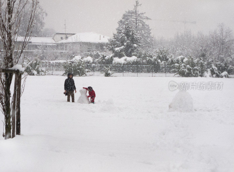 妈妈和女儿在一场大雪下堆雪人