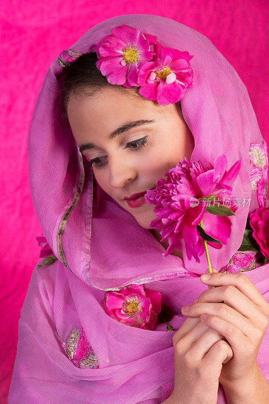 十几岁的女孩在粉红色的围巾拿牡丹。