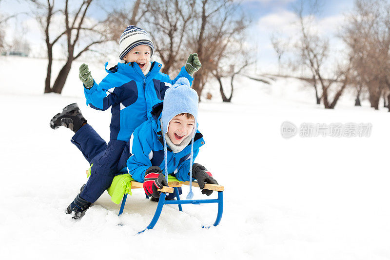 两个小男孩在公园里滑雪橇