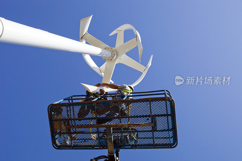 在晴朗的蓝天下安装垂直风力涡轮机叶片的工人
