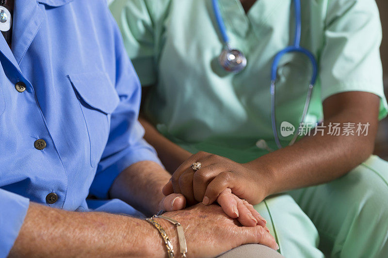 医疗:家庭保健护士与老年妇女牵手。