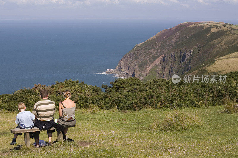 一家人坐在木凳上欣赏海岸景色