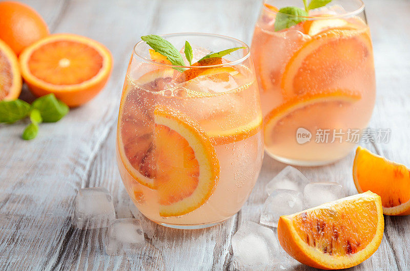 在木制背景下，用玻璃杯盛有血橙片的清凉饮料。