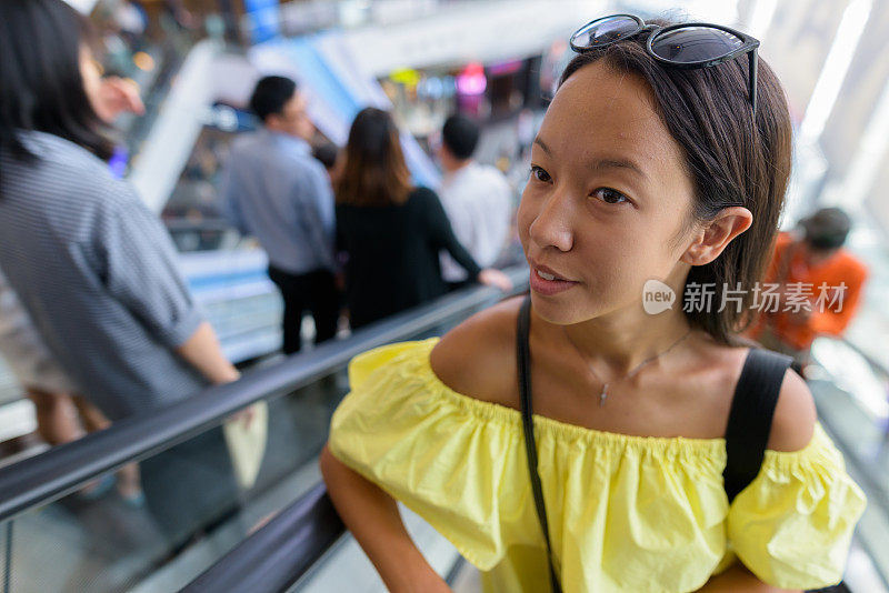 年轻美丽的多民族旅游女人的肖像徘徊在商场在泰国曼谷