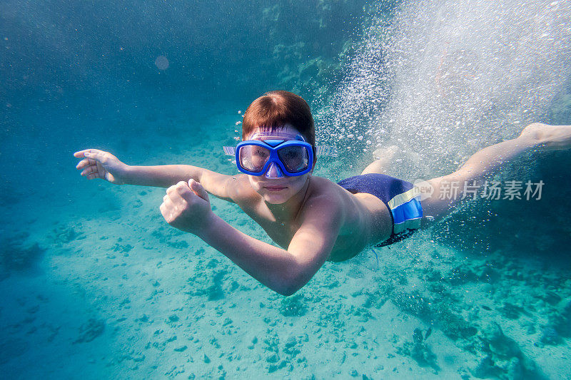 戴着游泳面具的男孩在珊瑚礁附近的红海深处潜水