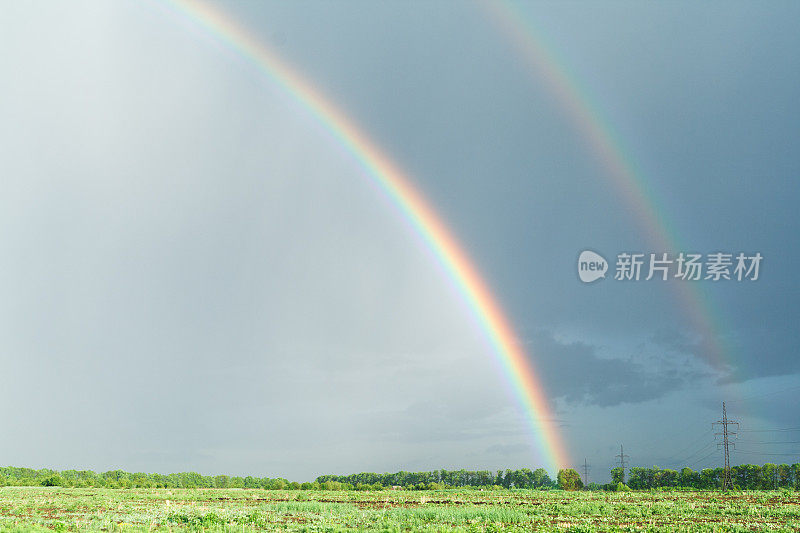 彩虹掠过绿色的田野。景观背景