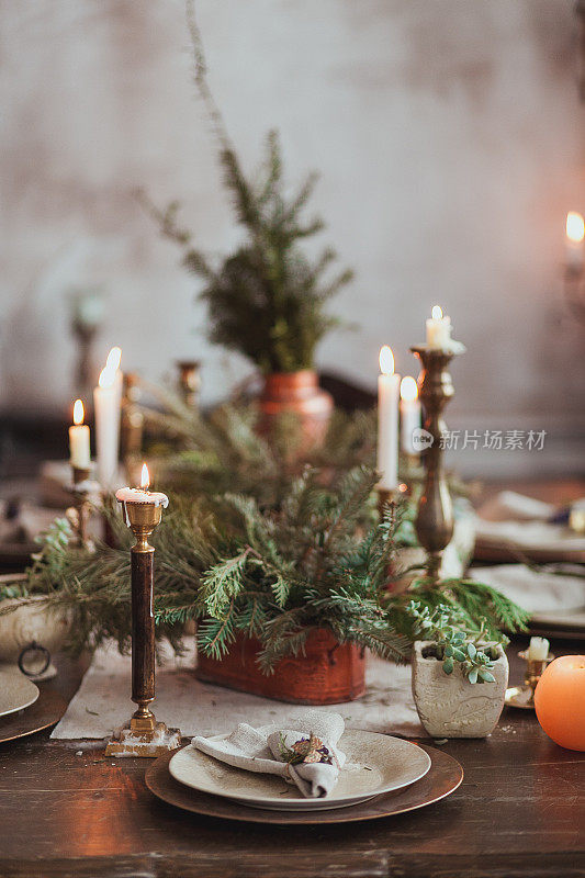 圣诞家庭餐桌概念。蜡烛，古董盘子，杉木树枝，墙上有清晰的复制空间