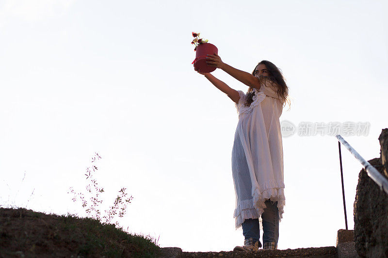 一个年轻女子在花盆里献上一株植物