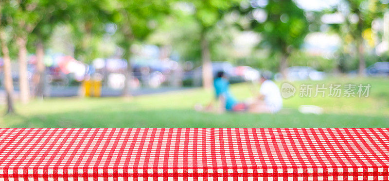 空桌子与红色格子桌布上模糊公园与人和散景背景，横幅，食品和产品展示蒙太奇
