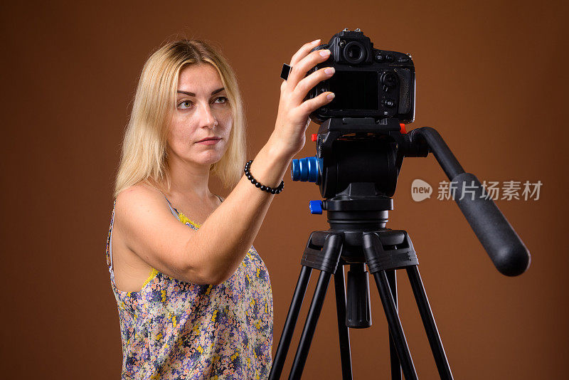 工作室拍摄的成熟的金发女人准备在彩色背景下做视频博客