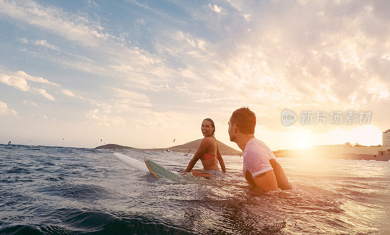 适合夫妇在日落冲浪-冲浪者的朋友在海洋里有乐趣-极限运动和度假概念-关注男人的头-原始的太阳颜色的色调