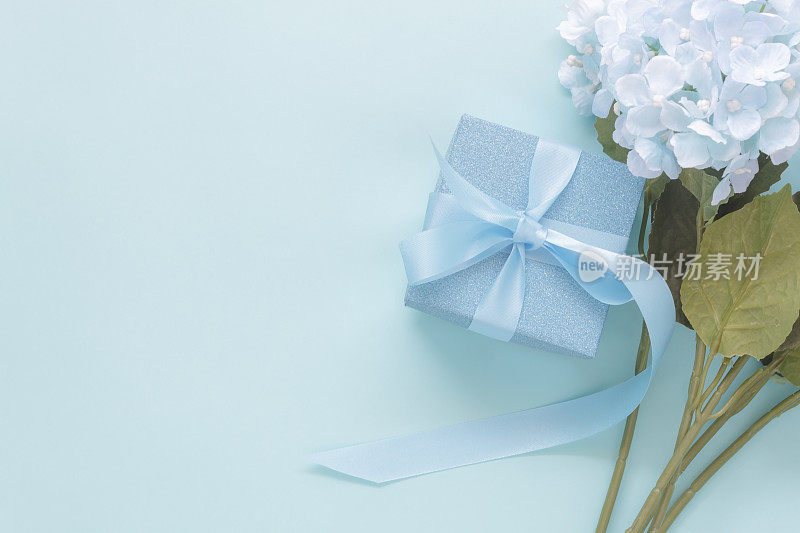 俯视图航拍装饰母亲节节日背景概念。平躺礼盒与蓝色花在现代美丽的蓝色纸在家庭办公书桌。设计的自由空间。
