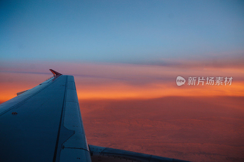 夕阳中沙漠上空的飞机机翼