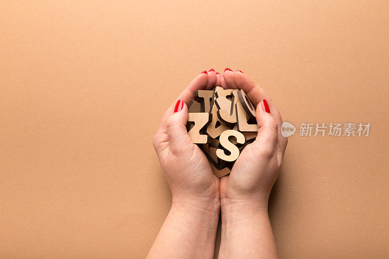 一个女人拿着米色背景上的木头字母