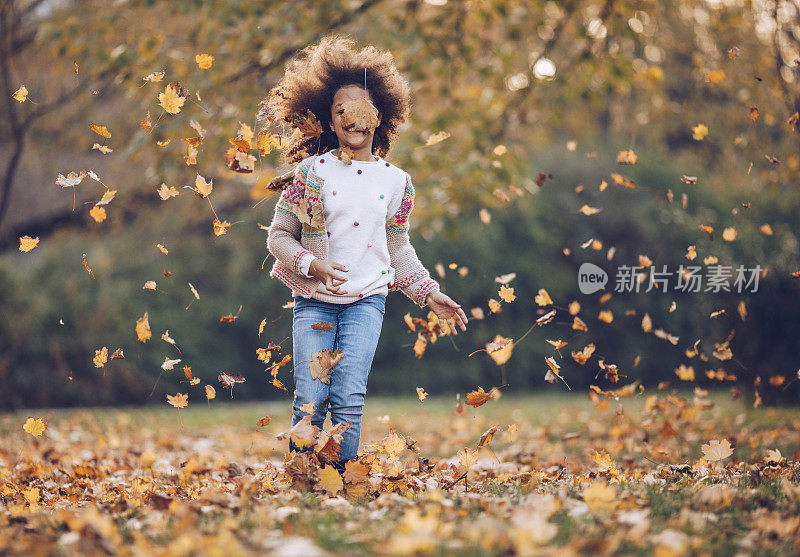 无忧无虑的非裔美国女孩在秋天的一天在公园里跑步。
