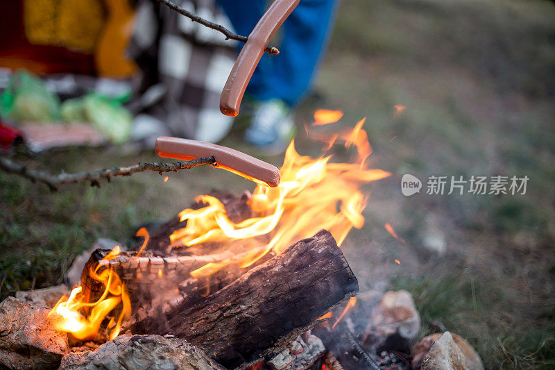 漂亮的一对，围坐在篝火旁。背景是一个帐篷，那人用一根棍子弹火。