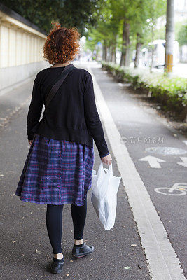 日本京都，一名妇女提着包走在人行道上