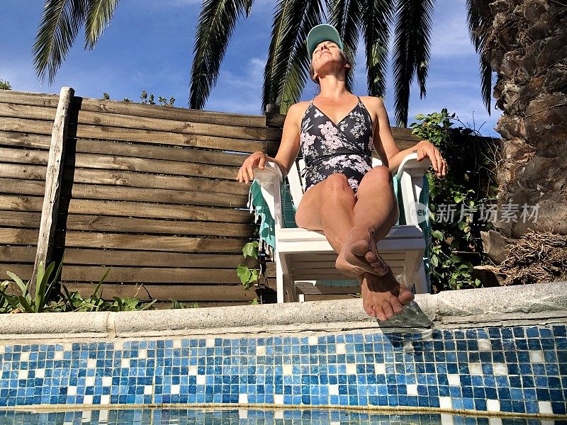 女性在泳池旁边的椅子上晒太阳