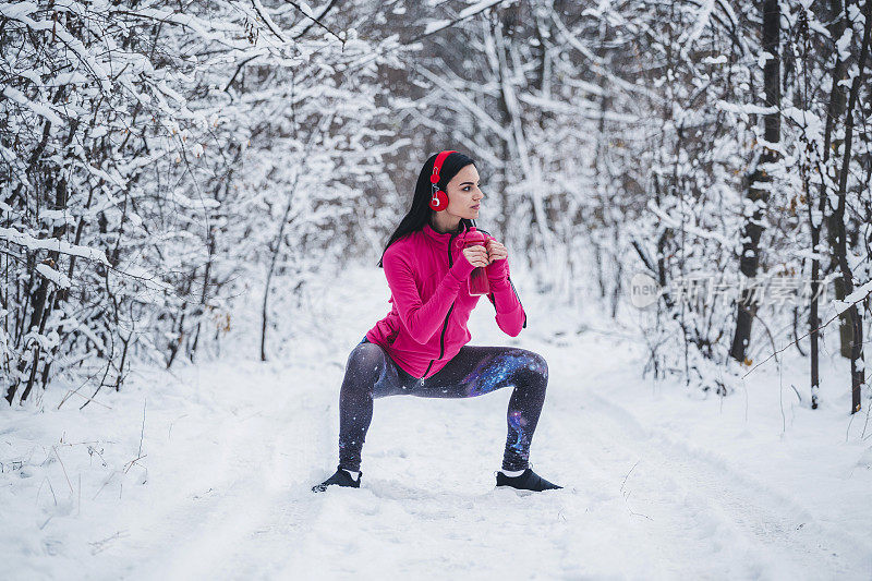 年轻的健康女子在冬天雪地里做弓步运动