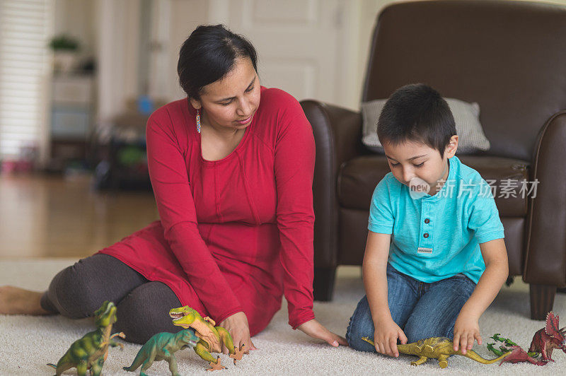 印第安母亲和她的儿子在客厅里玩恐龙