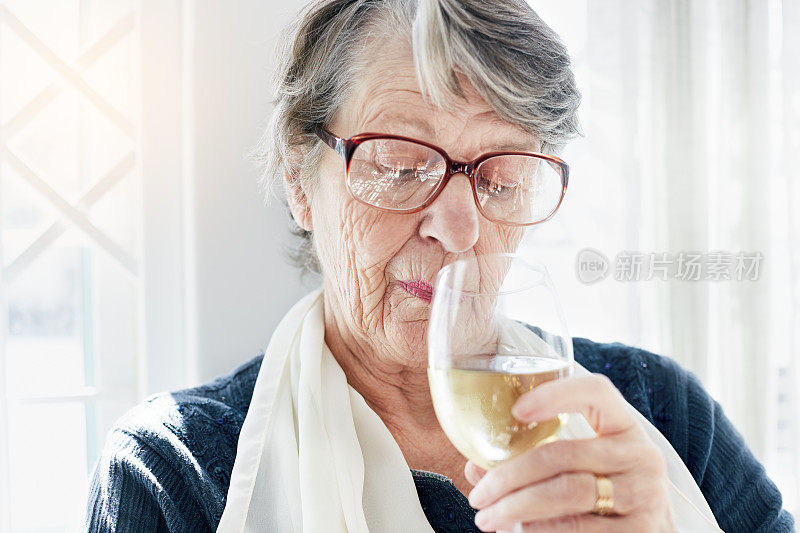 资深女士欣赏地嗅着酒杯