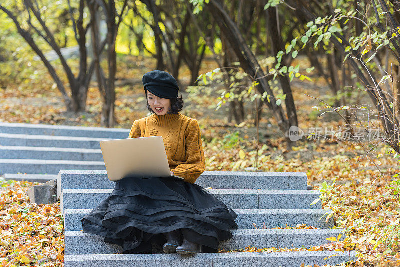 一个亚洲女孩在公园里操作笔记本电脑