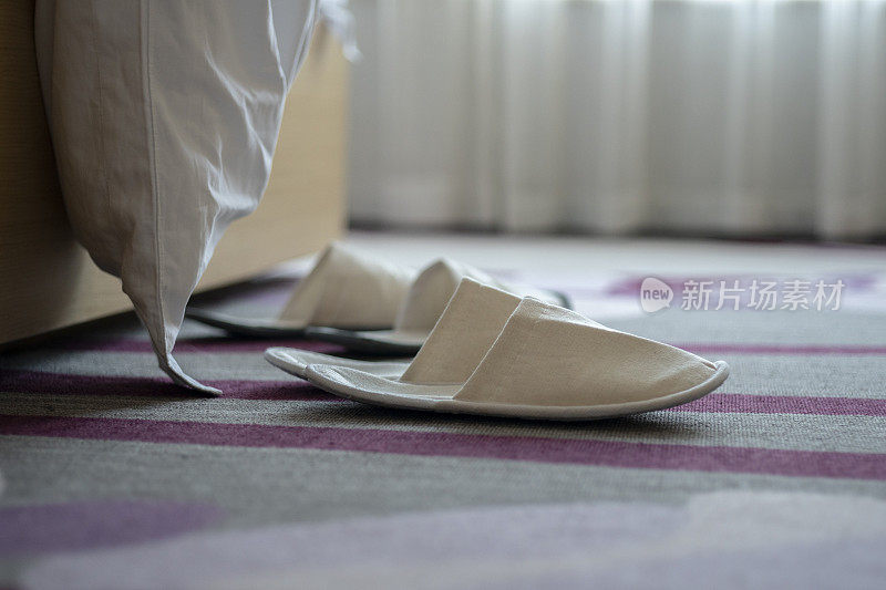 酒店的拖鞋放在床边的地毯上