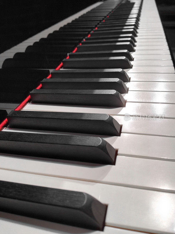 大钢琴键盘的特写，漂亮的乐器，在移动设备上拍摄的暗光