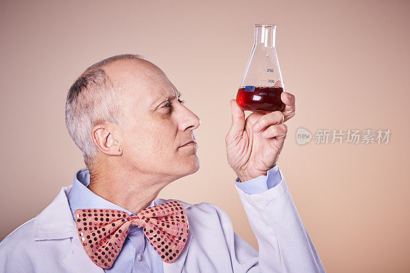 一位古怪的科学家皱着眉头检查着装有红色液体的瓶子