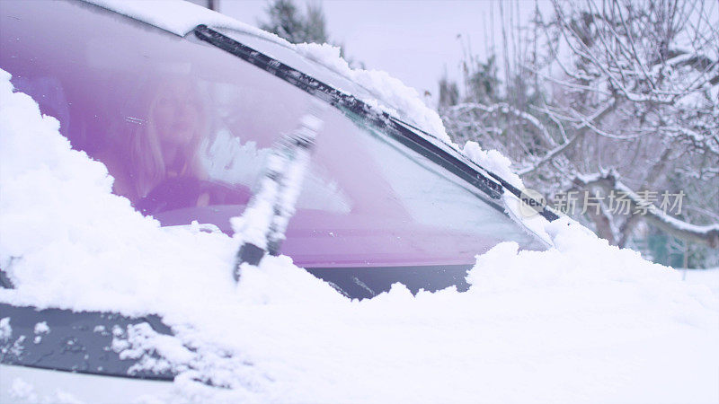 汽车刮擦窗户上的雪。冬季开车