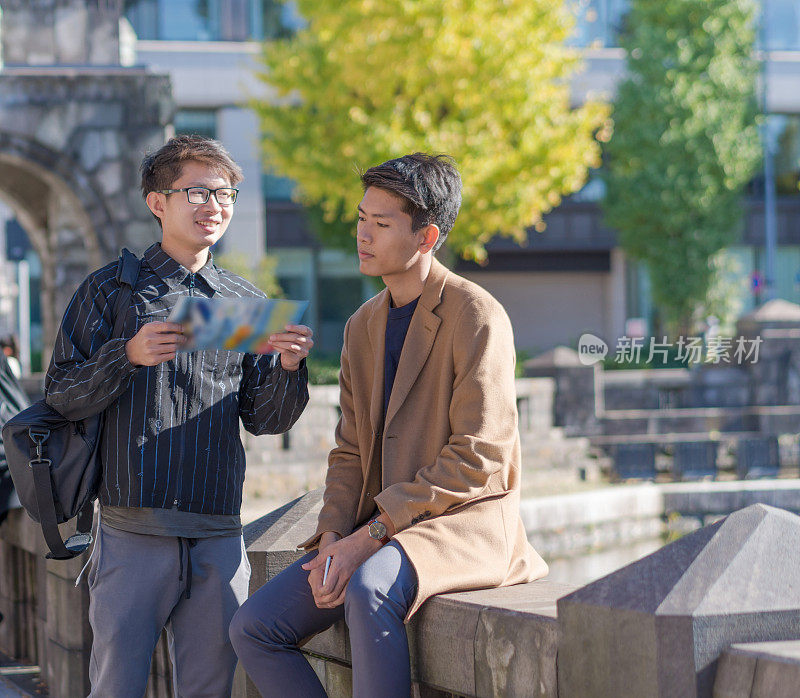 年轻的亚洲男子和日本朋友寻找旅游地点使用手机和花时间在亚洲旅行