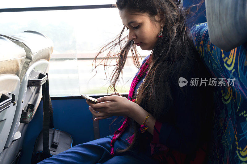 美丽的亚洲女孩旅行和使用智能手机在公交车上