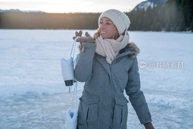 夕阳西下，年轻女子肩挎冰鞋走在结冰的湖面上，享受着寒假的乐趣