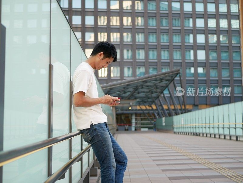 一名成年日本男子正在街上使用智能手机。