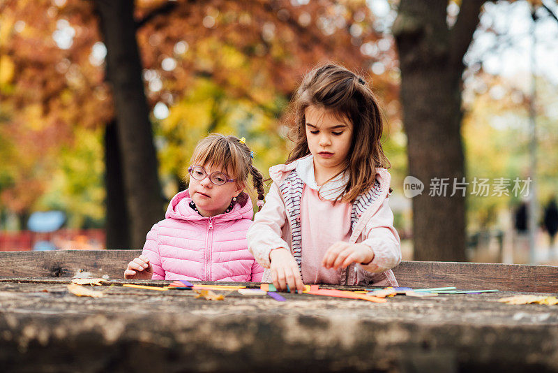 一个患有唐氏综合症的女孩和她的妹妹在公园里玩耍