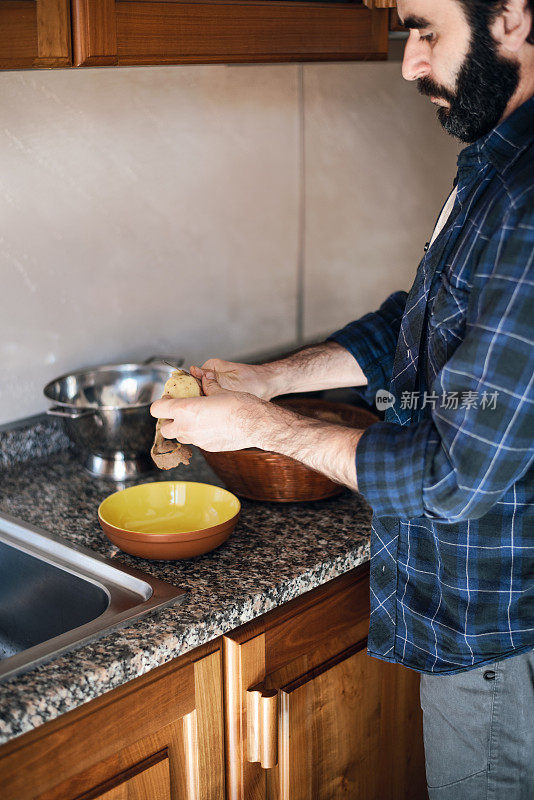 隔离烹饪:一名男子在煮土豆之前剥土豆皮