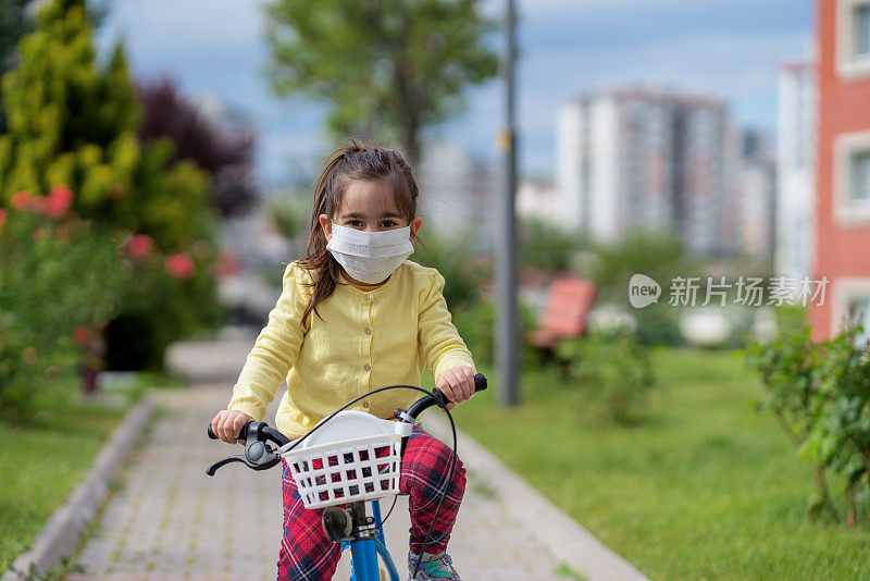 小女孩戴着防护面罩骑自行车