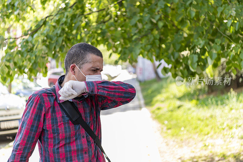 街上一名男子因潜在的病毒症状而咳嗽。