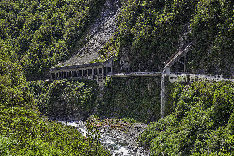 新西兰南岛南阿尔卑斯山脉上的亚瑟山口公路。狭窄的道路被覆盖，以防止岩石落在路上。