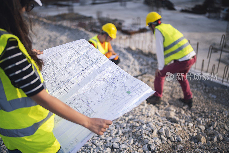 在建筑工地上拿着设计图的建筑师。