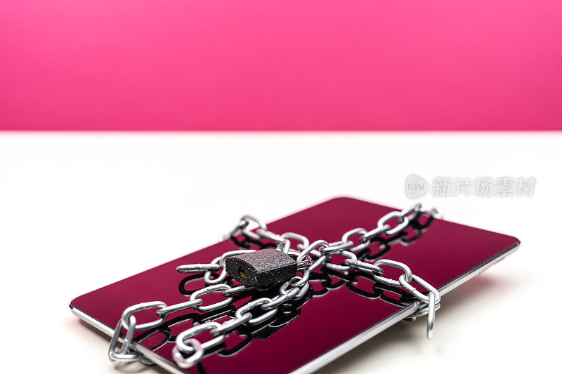 数字平板电脑与挂锁和链在粉红色的背景