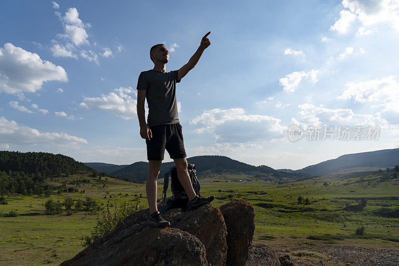 旅行者用背包跳跃的手举起山峦景观为背景生活方式旅行快乐情感成功概念夏日户外度假