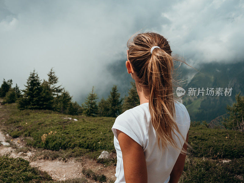 年轻女子在山径上凝视着眼前的景色