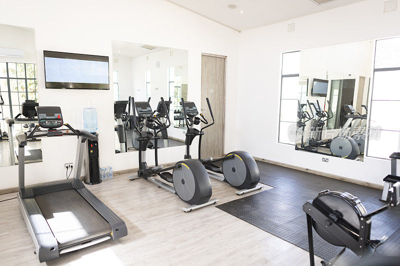 小健身房的健身器材，墙上有电视屏幕