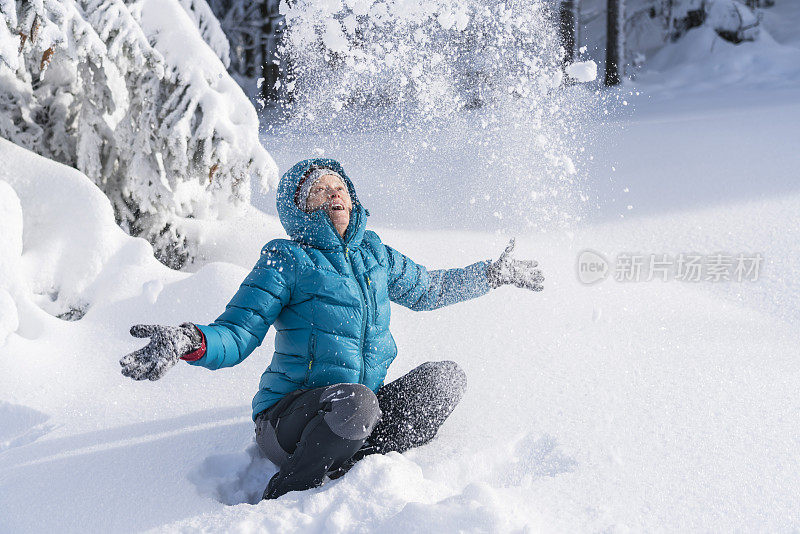 在冬天的森林里，成熟的女人穿着皮大衣向空中抛雪