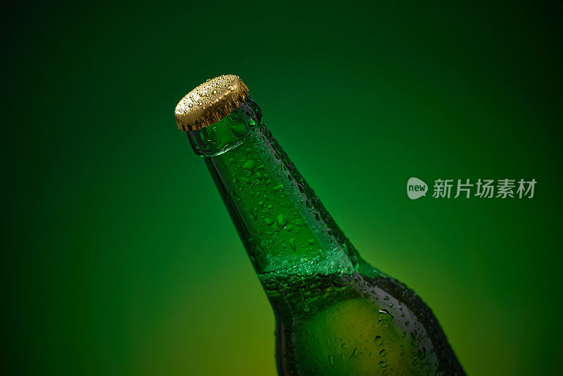 特写的完整未打开的瓶子与滴和金色的盖在绿色的背景。库存图片