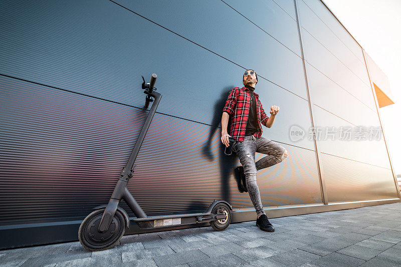 一个年轻人骑着他的电动摩托车。技术、生态的移动性概念。一个骑着电动踏板车的潮人。