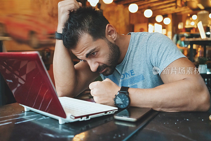 一名男子在咖啡店使用笔记本电脑