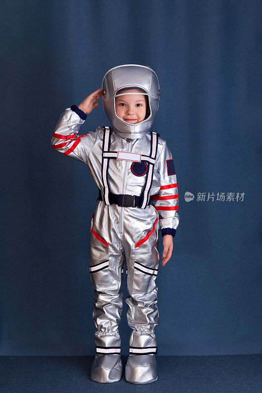 宇航员的概念。小男孩的肖像在宇航员服装和头盔上的蓝色背景。